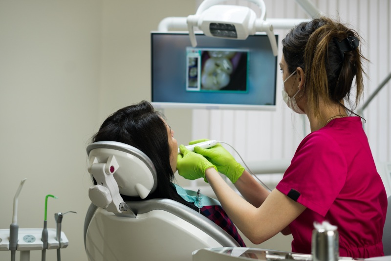 dentist working on tooth while patient and dentist look at tooth on monitor